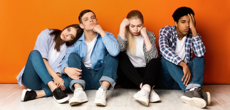Groupe d'adolescents français assis par terre devant un mur orange